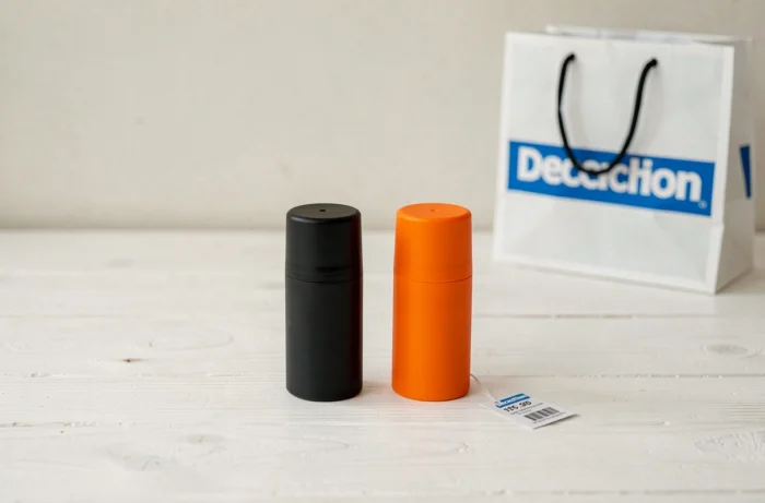 Comparaison de deux bombes anti agression Decathlon avec étiquette de prix sur table en bois